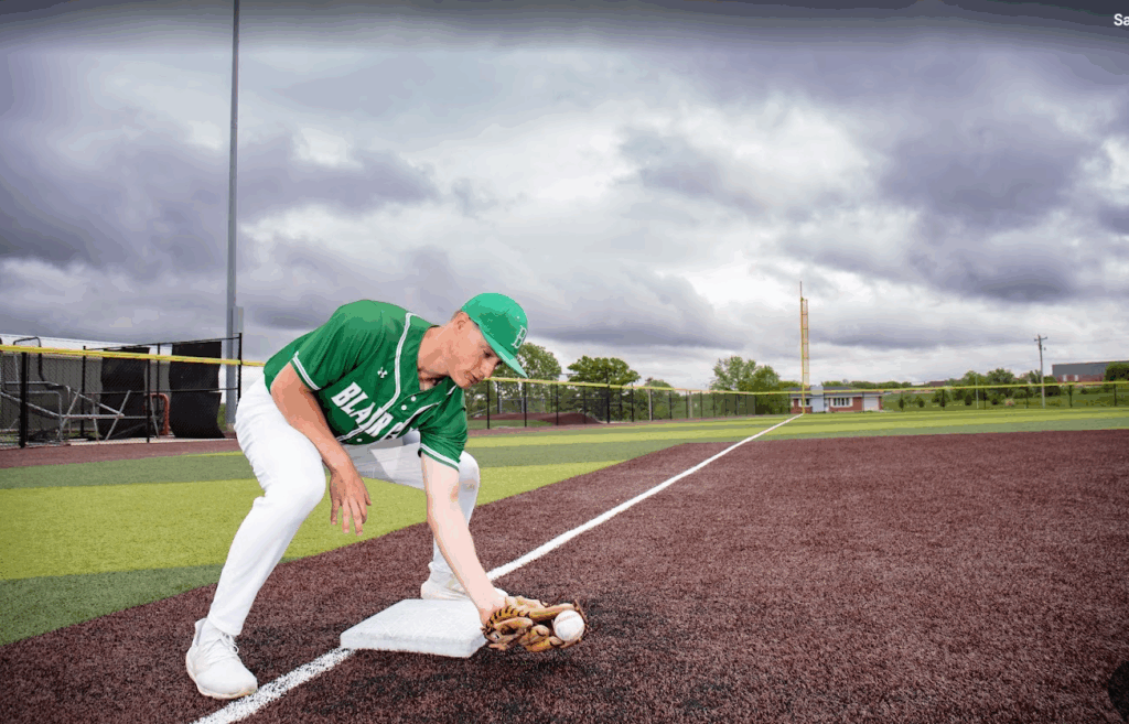 male student-athlete on third base scooping up ball with glove